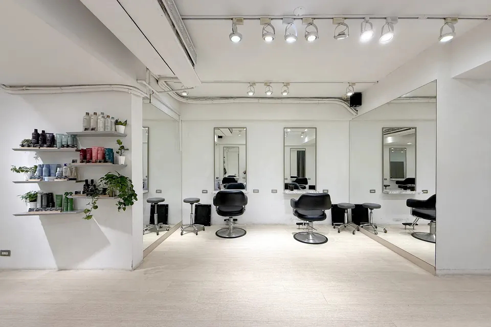 沙龍內明亮的白色空間，牆面層架陳列 Aveda 髮品與綠植