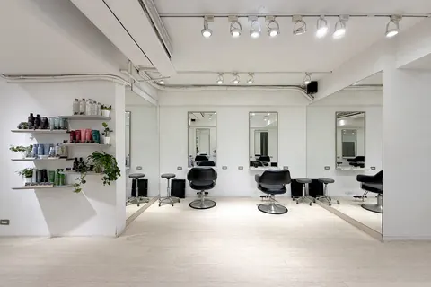 沙龍內明亮的白色空間,牆面層架陳列 Aveda 髮品與綠植