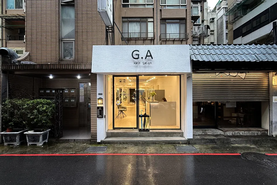 G.A Hair Salon 忠孝東路 216 巷店面外觀，雨後夜色中的白色招牌與明亮落地窗